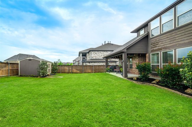 View of yard featuring a storage unit, an outdoor structure, and a patio area | Image 35