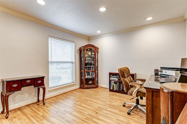 Positioned beside the dining area in an open layout, this spacious office area remains well-connected to the main living spaces. A large window invites in natural light, while recessed lighting ensures consistent illumination. Its airy feel and convenient location makes it an ideal place for productivity. | Image 11