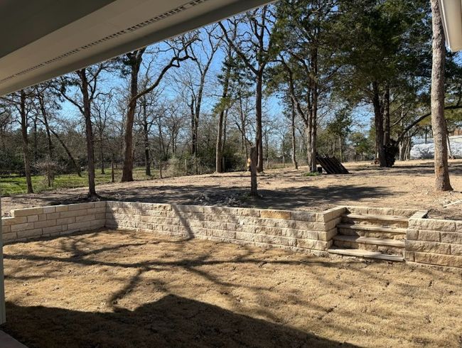 A charming covered back patio with a stylish ceiling fan, ideal for year-round relaxation, overlooking a beautifully landscaped backyard. | Image 39