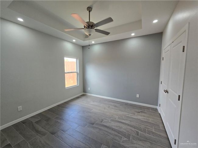 Empty room with a ceiling fan, recessed lighting, a raised ceiling, and baseboards | Image 15