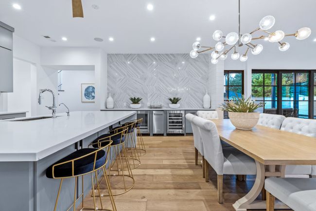 Dining room with recessed lighting, light wood-style floors, beverage cooler, a chandelier, and bar area | Image 13