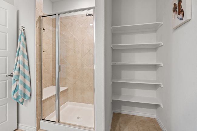 Primary Bathroom with tile floors, Walk In shower with seating, baseboards and Linen Shelves | Image 20