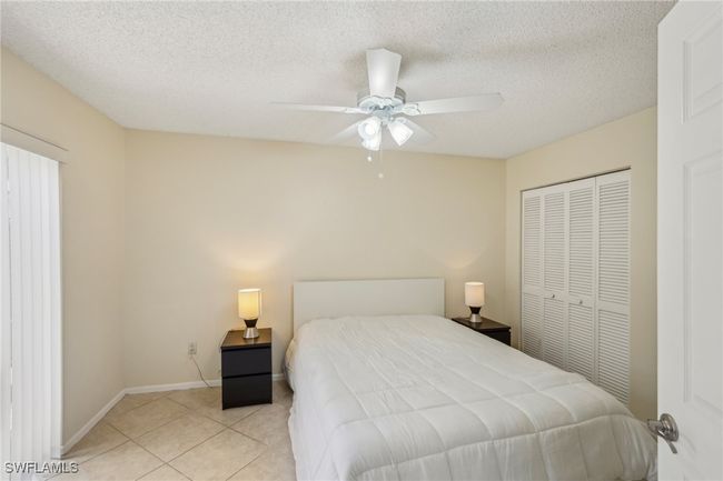 Bedroom with a textured ceiling, a ceiling fan, a closet, and tile patterned flooring | Image 16