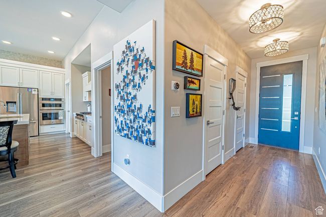 Foyer entrance with light wood finished floors, a chandelier, baseboards, and recessed lighting | Image 14