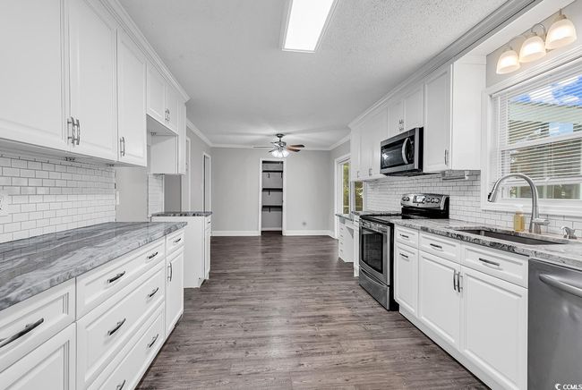 Kitchen with appliances with stainless steel finishes, white cabinets, backsplash, and ornamental molding | Image 15
