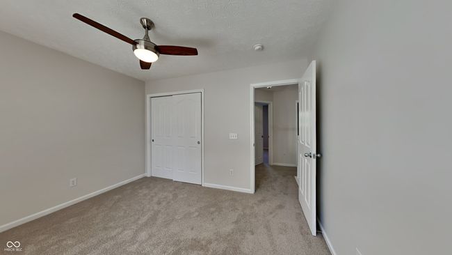 unfurnished bedroom with baseboards, light colored carpet, a closet, ceiling fan, and a textured ceiling | Image 14