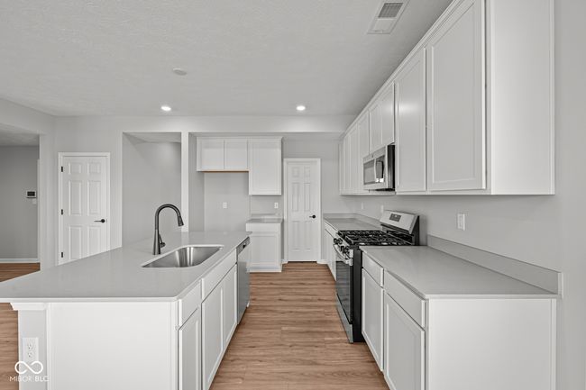 kitchen with a sink, white cabinetry, stainless steel appliances, light wood-style floors, and recessed lighting | Image 7
