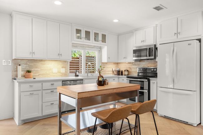 Kitchen featuring white cabinets, glass insert cabinets, appliances with stainless steel finishes, light countertops, and a sink | Image 16