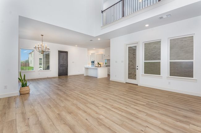Unfurnished living room with a chandelier, a towering ceiling, and light wood-style flooring | Image 11