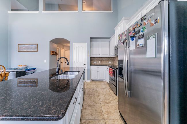 Kitchen featuring appliances with stainless steel finishes, a sink, arched walkways, decorative backsplash, and white cabinetry | Image 10