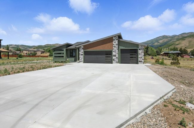 View of front of house featuring a mountain view, stone siding, a garage, and concrete driveway | Image 57