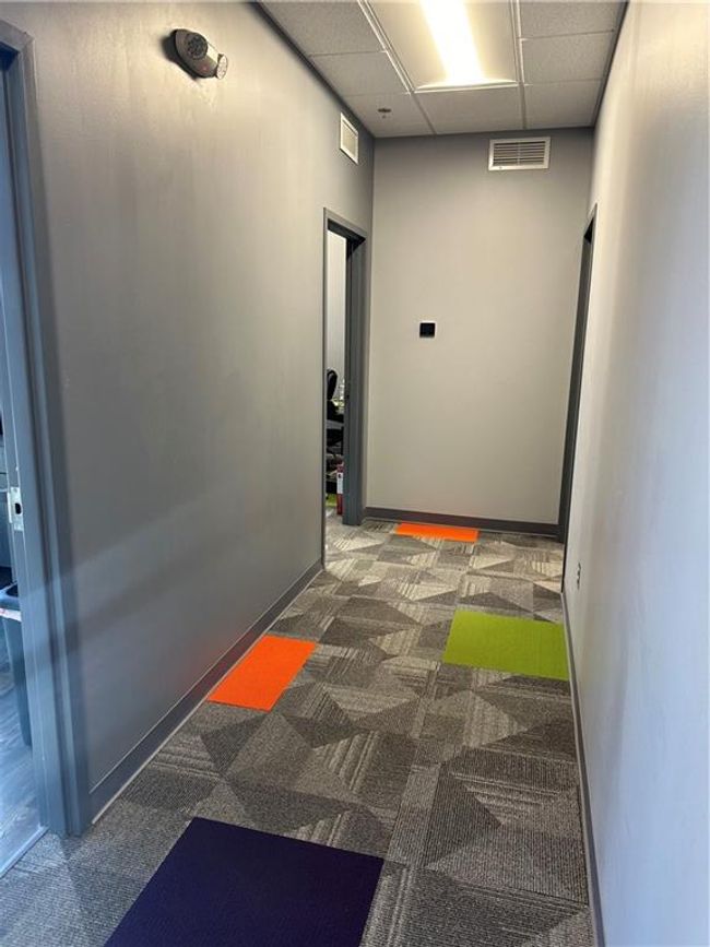 Hall featuring a paneled ceiling and dark colored carpet | Image 18