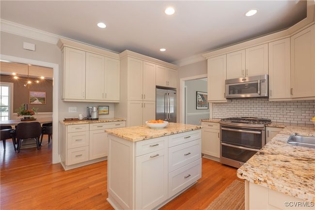 Kitchen featuring crown molding, backsplash, appliances with stainless steel finishes, and light wood finished floors | Image 17