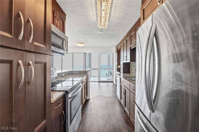 Kitchen featuring decorative backsplash, light stone counters, a notable chandelier, and stainless steel appliances | Image 14