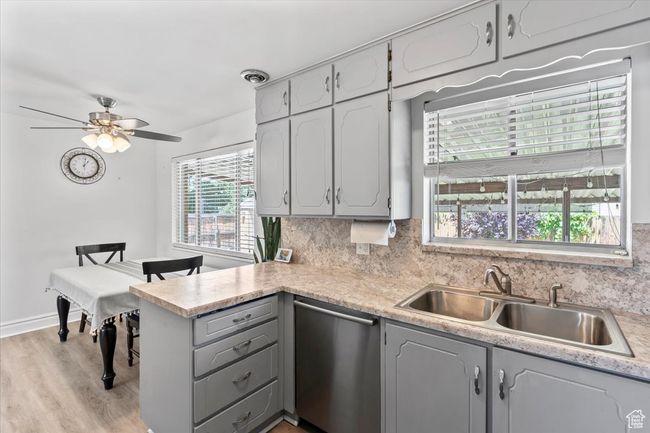 Kitchen featuring stainless steel dishwasher, a sink, gray cabinets, a peninsula, and tasteful backsplash | Image 10