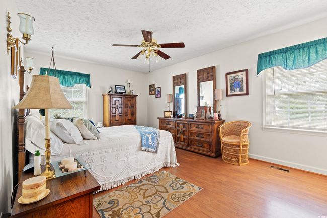 Bedroom with baseboards, wood finished floors, visible vents, and a textured ceiling | Image 13