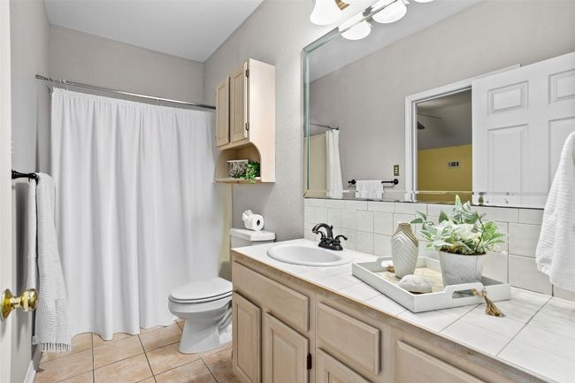 Bathroom with vanity, toilet, tile patterned floors, decorative backsplash, and a shower with curtain | Image 25