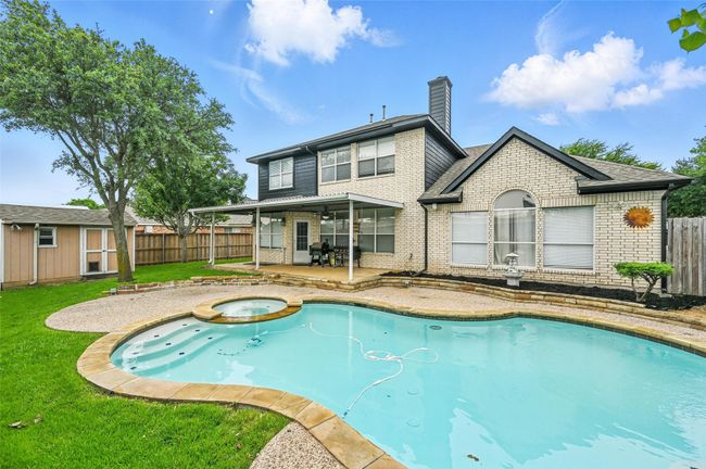 View of swimming pool with a patio area, a fenced backyard, an outdoor structure, and a pool with connected hot tub | Image 31