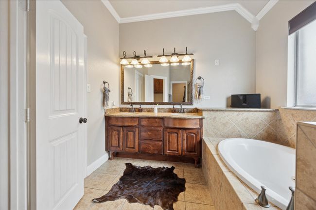 Bathroom featuring double vanity, a bath, crown molding, and tile patterned floors | Image 13
