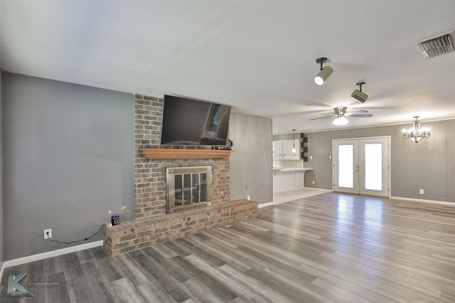 Unfurnished living room with a fireplace, french doors, ceiling fan with notable chandelier, and hardwood / wood-style flooring | Image 8