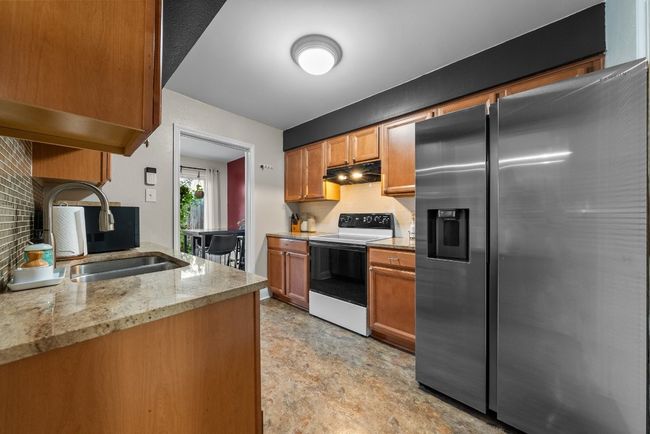 Kitchen with Quartz Countertops, Stainless Steel Refrigerator with ice dispenser, electric range and decorative backsplash | Image 7