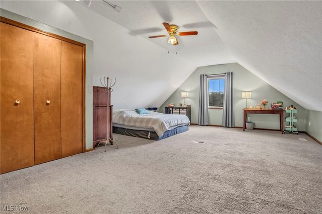 Bedroom with a textured ceiling, carpet flooring, ceiling fan, and vaulted ceiling | Image 28