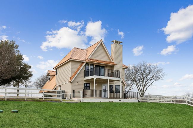 Back of property featuring a fenced front yard, a lawn, metal roof, and a balcony | Image 30