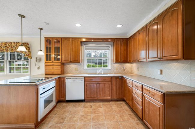 Kitchen featuring white appliances, brown cabinets, a peninsula, a sink, and a textured ceiling | Image 12