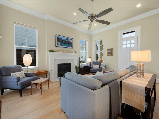Living area featuring light wood-style floors, ornamental molding, a ceiling fan, a glass covered fireplace, and recessed lighting | Image 4