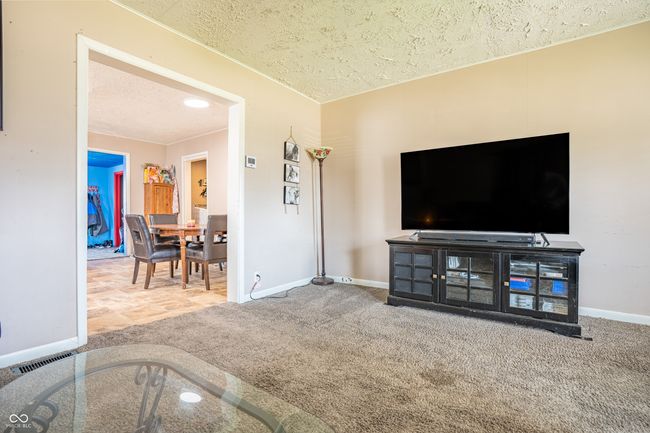 living room featuring carpet, a textured ceiling, baseboards, and visible vents | Image 6