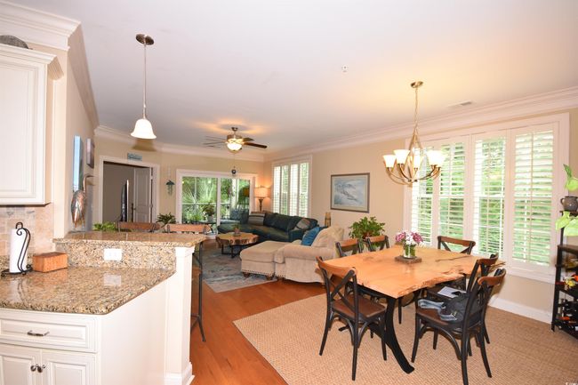 Dining area with light wood finished floors, a chandelier, ornamental molding, and a ceiling fan | Image 8