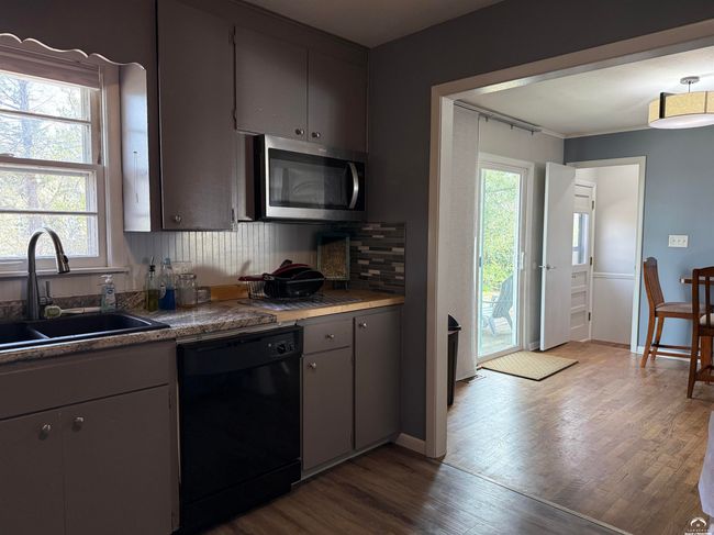 View to East from kitchen; Sliding door to deck; Dining room; Basement staircase w/ divisible access | Image 17