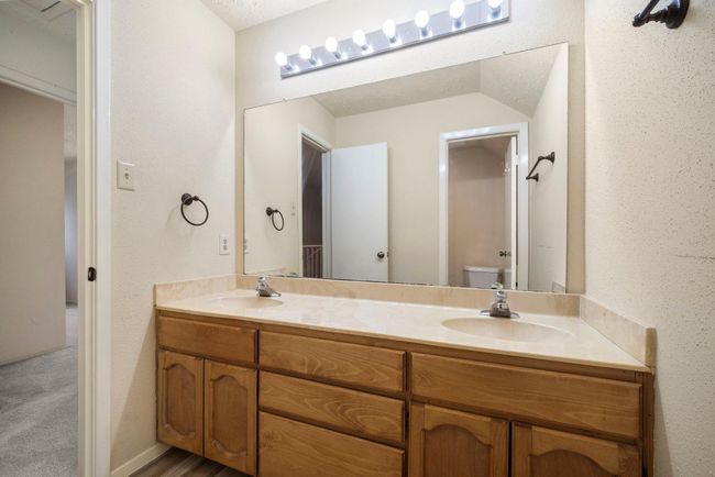 Double-sink vanity with extended countertop offers generous space for busy mornings, while a large wall mirror and ample cabinetry provide abundant storage. | Image 29