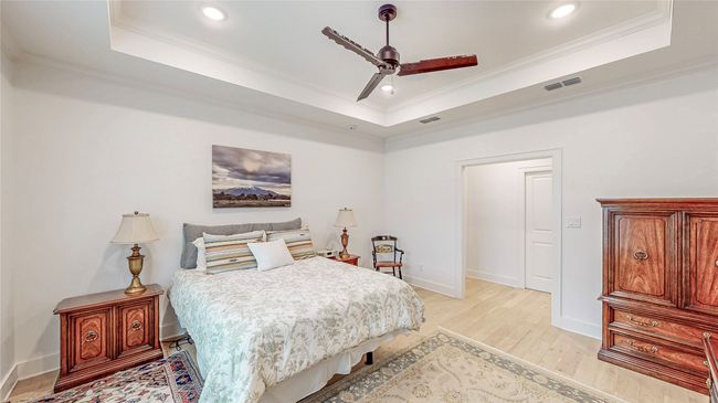 Bedroom featuring a raised ceiling, light wood finished floors, ornamental molding, recessed lighting, and a ceiling fan | Image 18