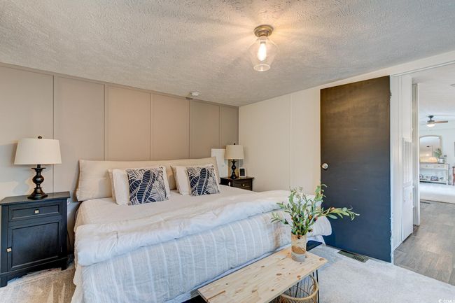 Bedroom featuring a decorative wall, a textured ceiling, and wood finished floors | Image 15