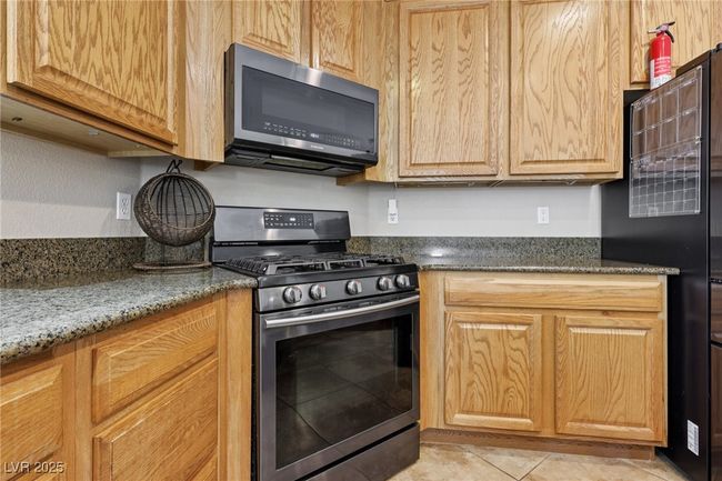 Kitchen featuring appliances with stainless steel finishes, light tile patterned floors, and dark stone counters | Image 26