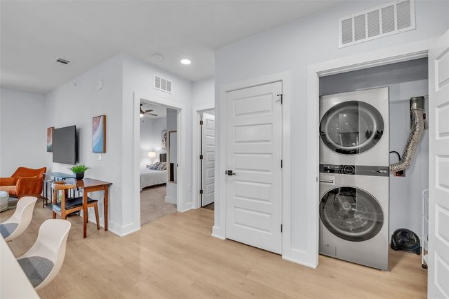 Laundry room with estacked washer and dryer, light wood-style floors, recessed lighting, and a ceiling fan | Image 24