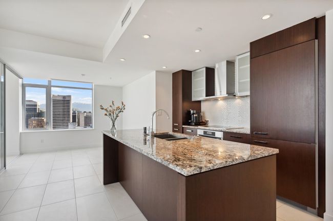 Kitchen with wall chimney range hood, tasteful backsplash, a sink, visible vents, and modern cabinets | Image 7