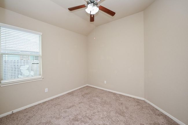 This bedroom #2 features carpet flooring with neutral walls, a ceiling fan with a light, and a window allowing natural light. | Image 12