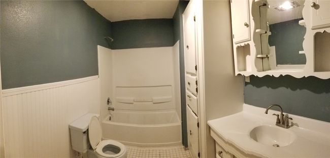 Full bath with bathtub / shower combination, vanity, a wainscoted wall, and tile patterned flooring | Image 12