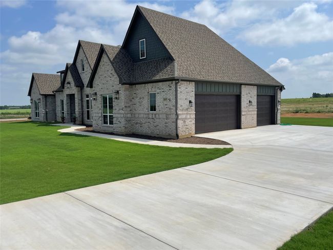 View of home's exterior with concrete driveway, a shingled roof, a lawn, brick siding, and a garage | Image 5