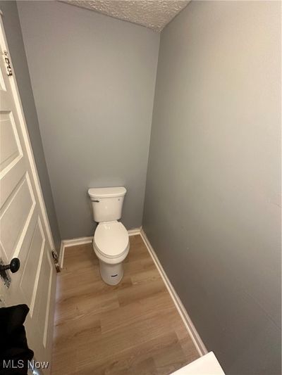 Bathroom featuring hardwood / wood-style flooring, toilet, and a textured ceiling | Image 3