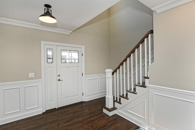 Foyer with dark wood finished floors, a decorative wall, crown molding, and wainscoting | Image 12