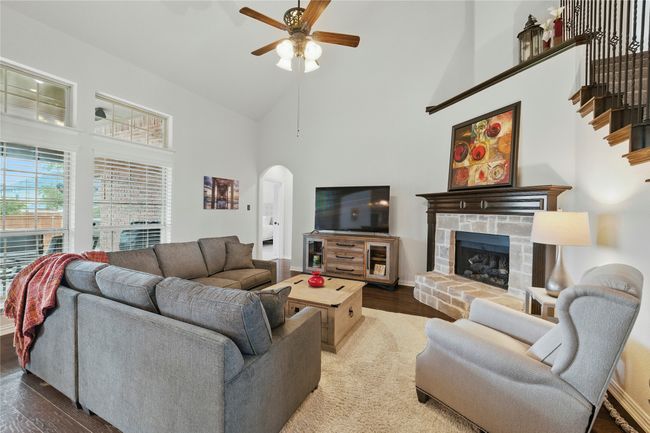 Living area featuring arched walkways, high vaulted ceiling, ceiling fan, wood finished floors, and a stone fireplace | Image 18