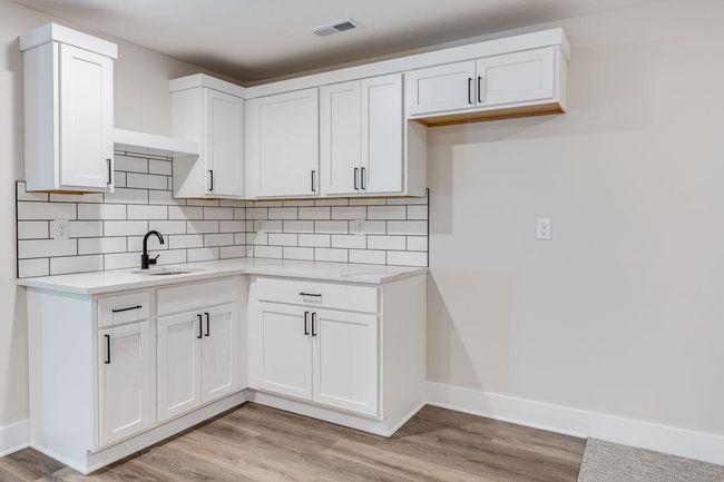 Kitchen featuring light wood-style flooring, a sink, white cabinets, and tasteful backsplash | Image 28