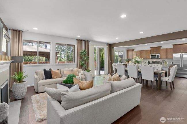 Bathed in natural light from large windows and sliding glass doors, the space flows seamlessly from the cozy living room with fireplace to the spacious dining area and gourmet kitchen. | Image 6