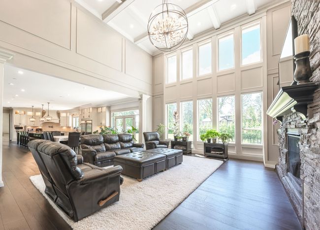 Living room featuring a high ceiling, decorative columns, a stone fireplace, and a chandelier | Image 8
