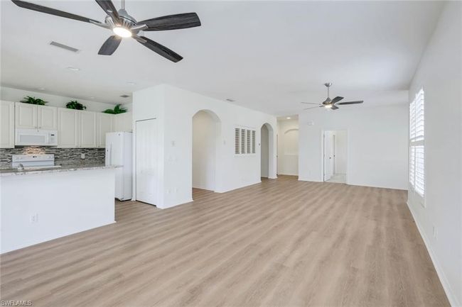 Unfurnished living room featuring open floor concept, with a ceiling fan, arched, and light wood-style floors | Image 6