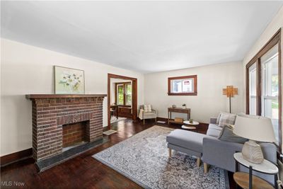 Living room with dark wood-type flooring, a healthy amount of sunlight, and a brick fireplace | Image 2