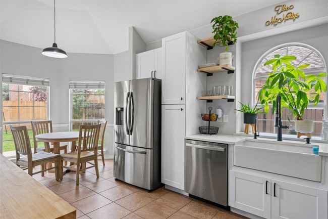 Kitchen featuring stainless steel appliances, open shelves, light countertops, white cabinets, and decorative light fixtures | Image 11